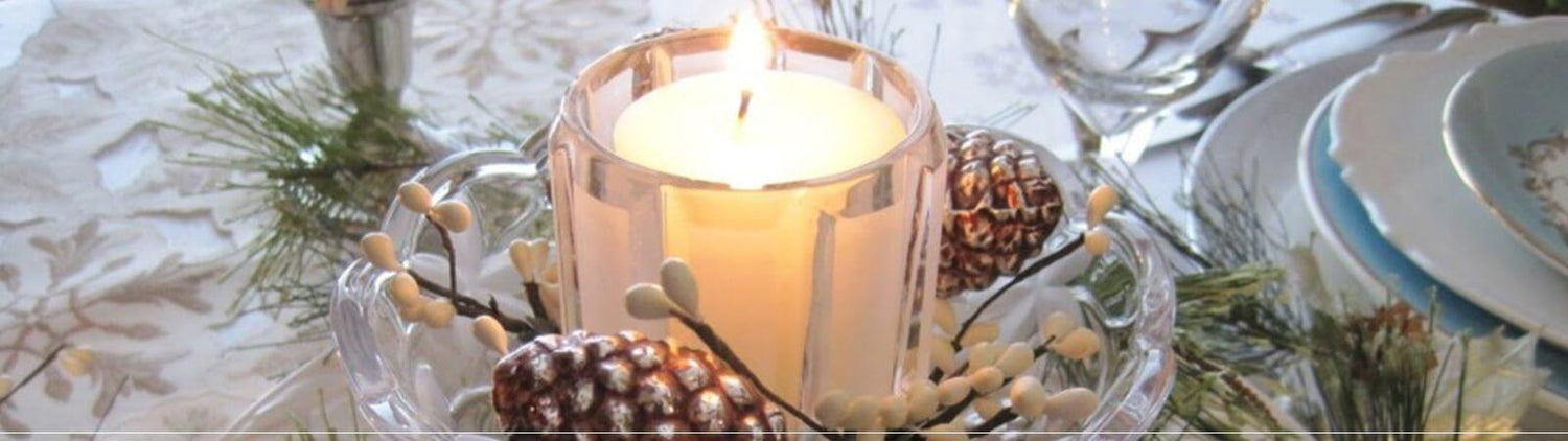 A candle centerpiece with pine cones and a glass holder.