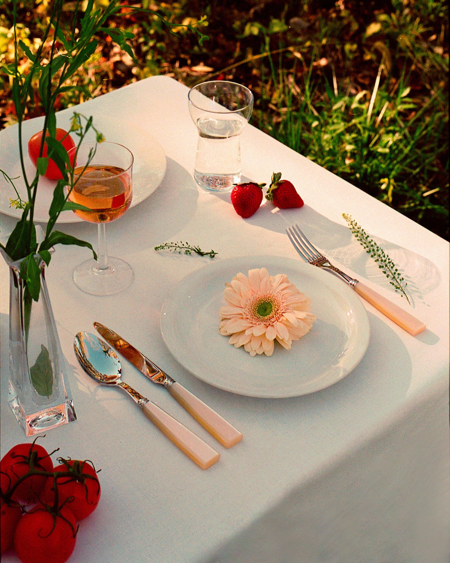 A plate with a flower and a glass of wine, part of the Pearl Cutlery Set of 5 from Party Social.