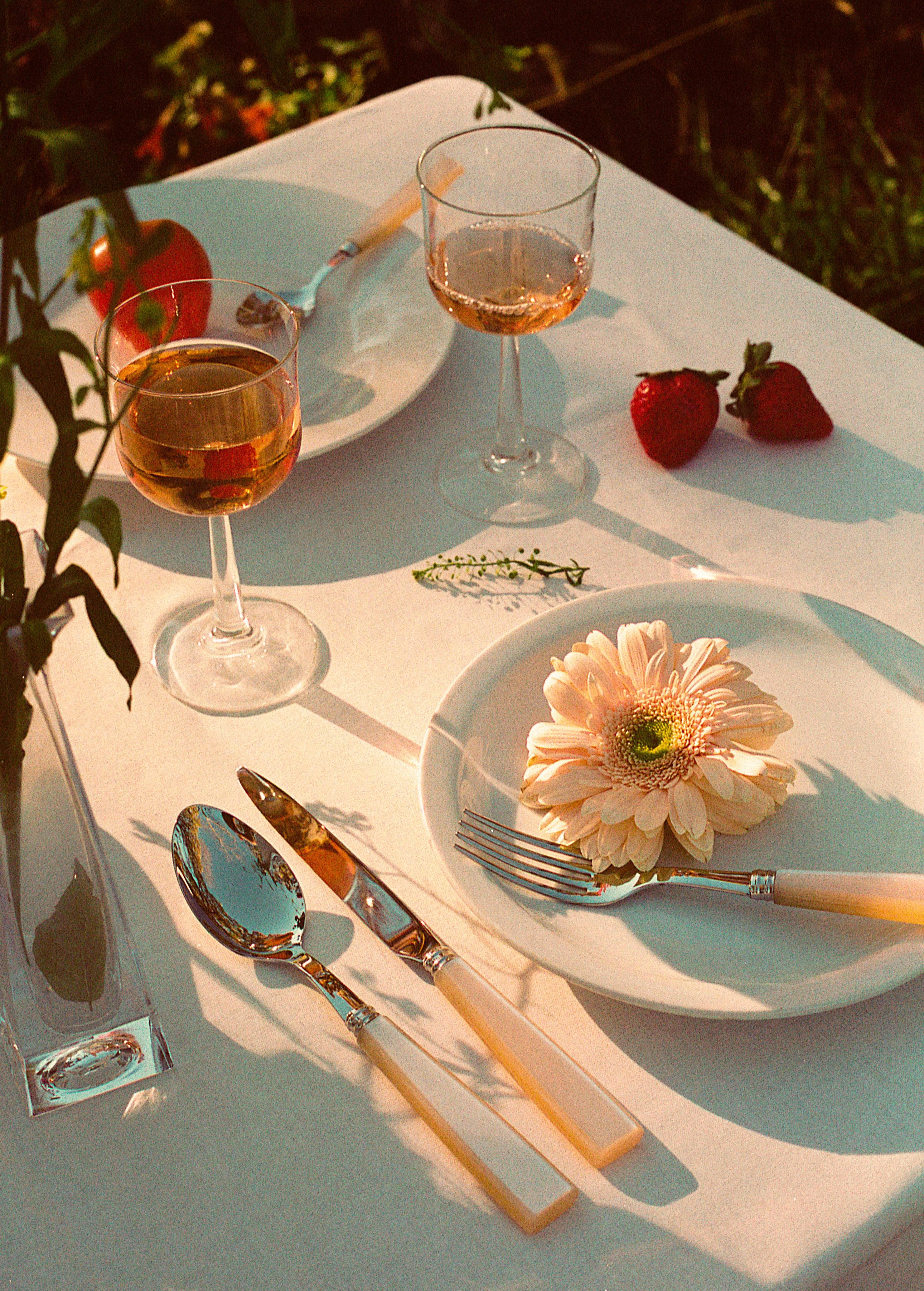 A stylish Pearl Cutlery Set of 5 on a table with a flower, fork, and spoon.