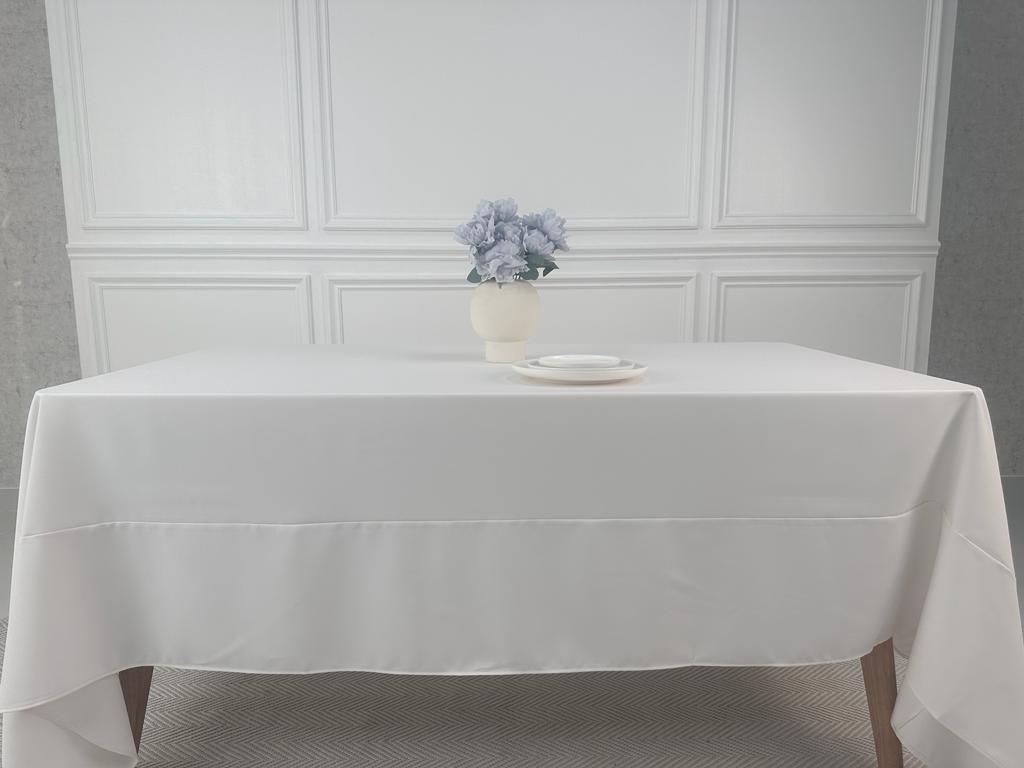 A Polycotton Tablecloth with a vase of flowers on a white table.
