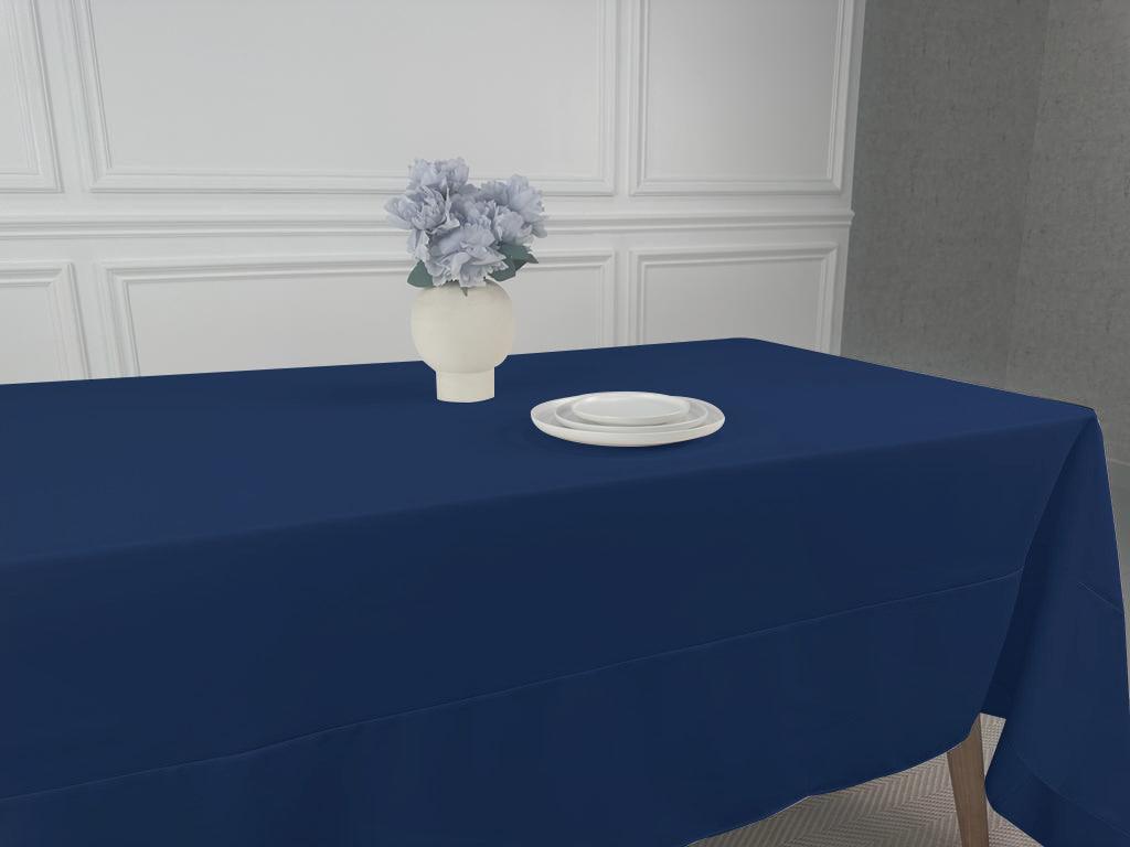 A simple tablecloth with a vase of flowers and a white plate on it.