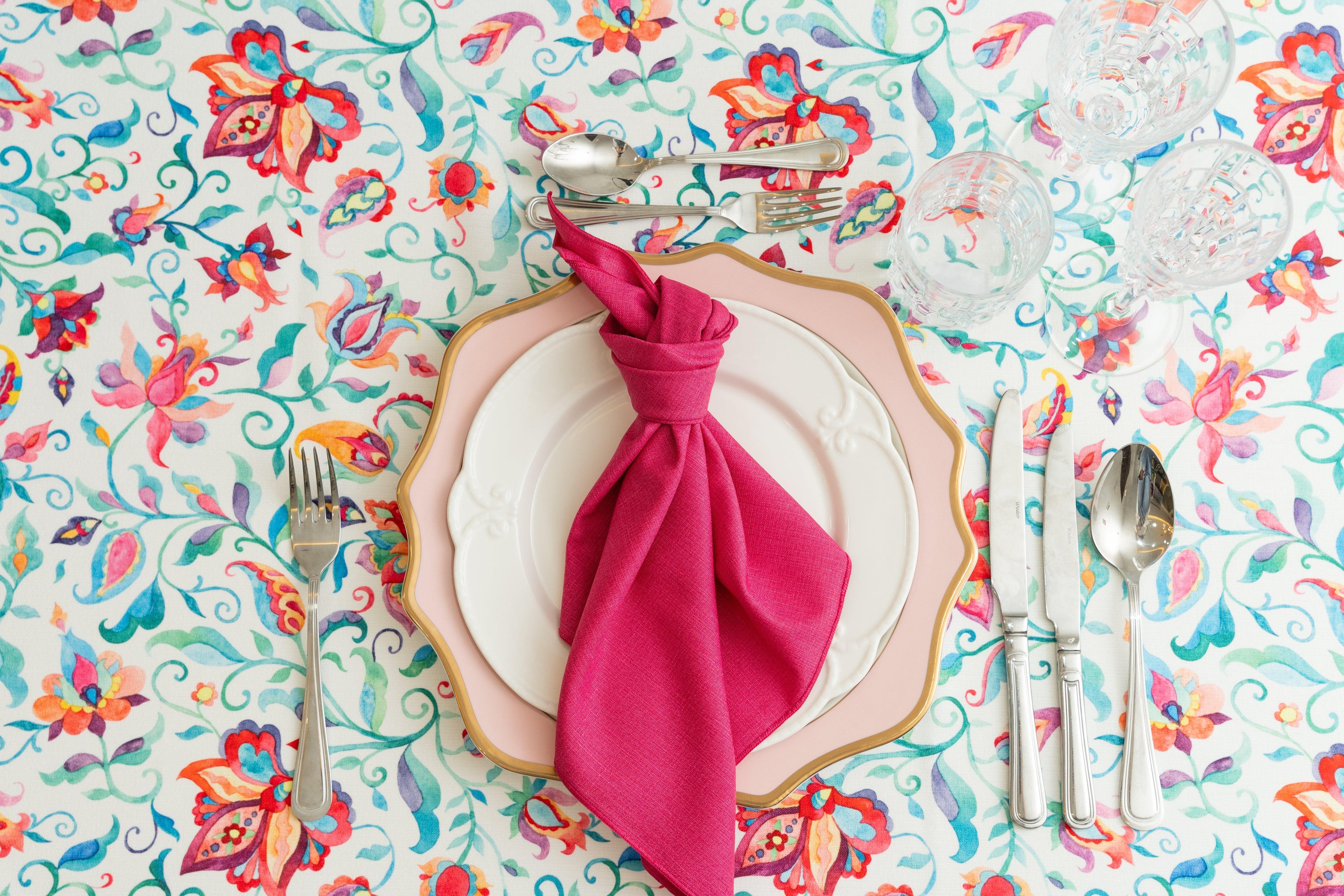 A plate with a napkin and silverware on a floral tablecloth
